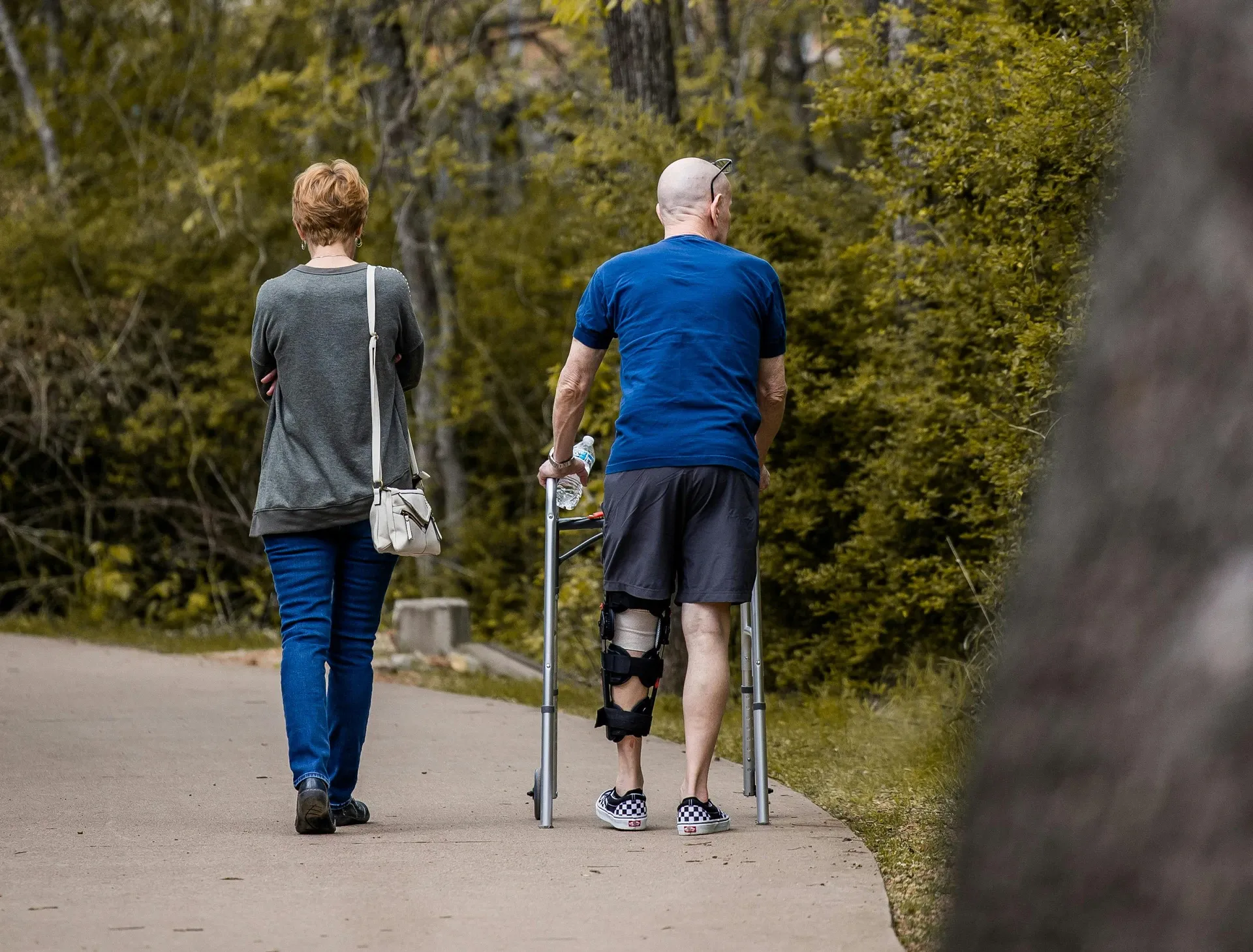 elderly couple walking together with man on crutches