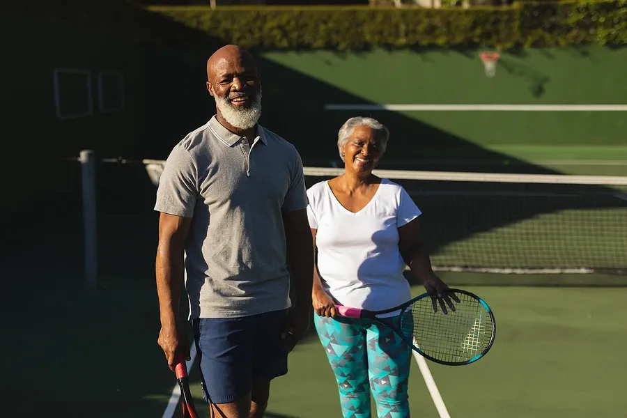 happy senior couple posing with tennis rackets