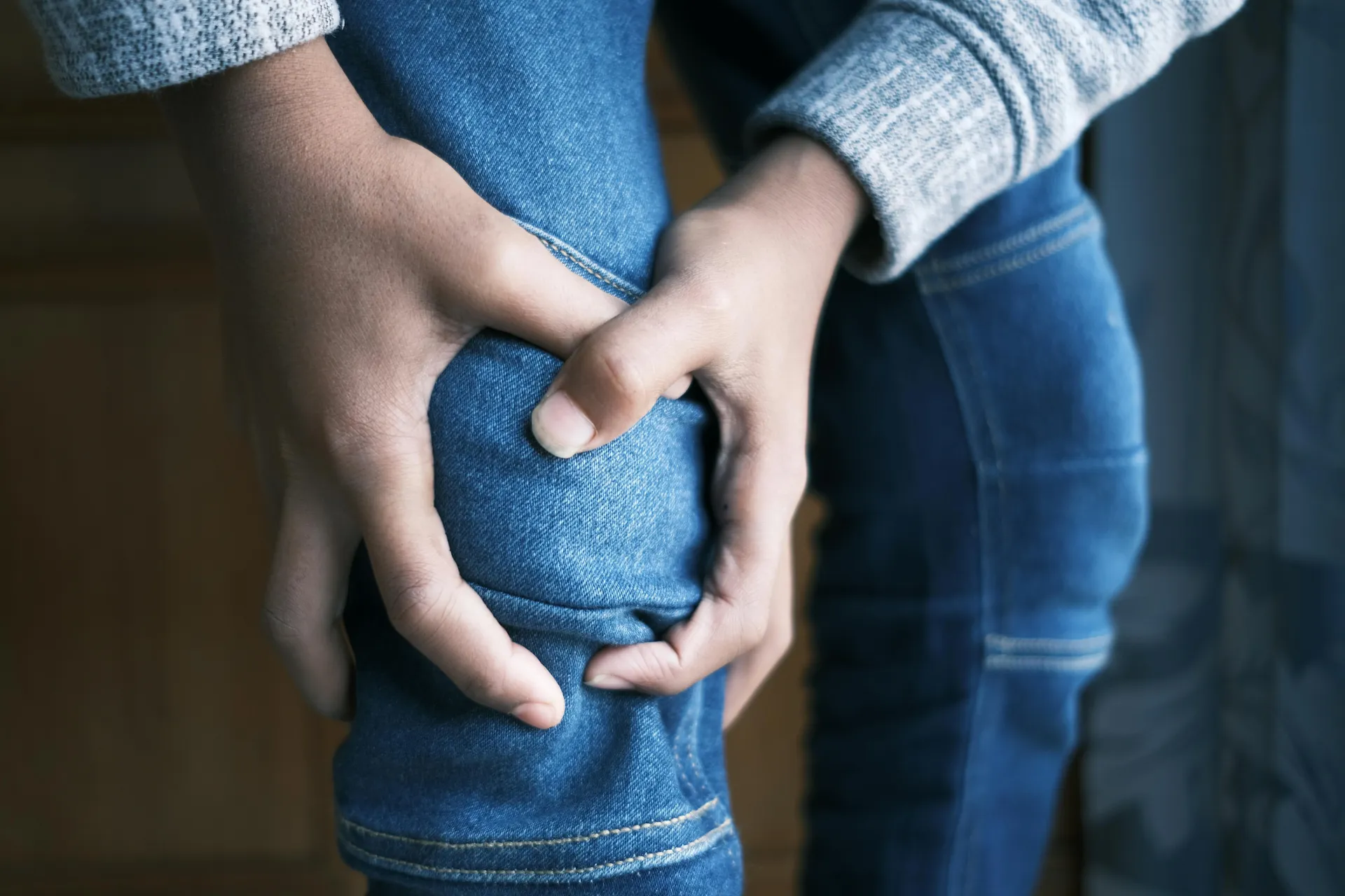 up close of person holding knee in pain indicating joint dislocation