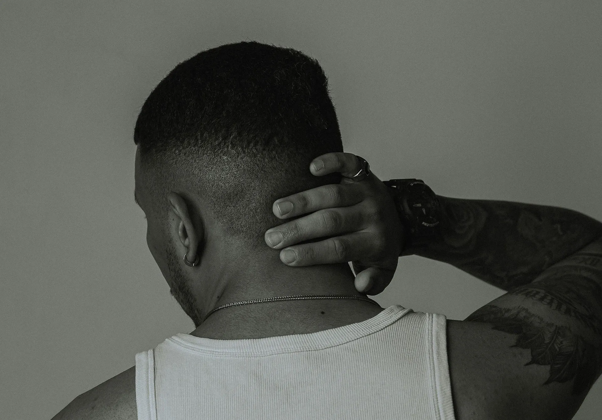 man holding back of lower head indicating pain from neck strain