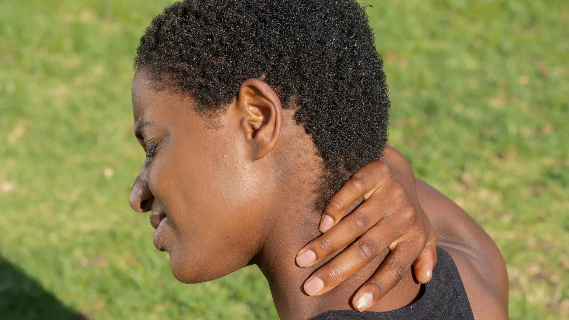 person holding back of neck in pain