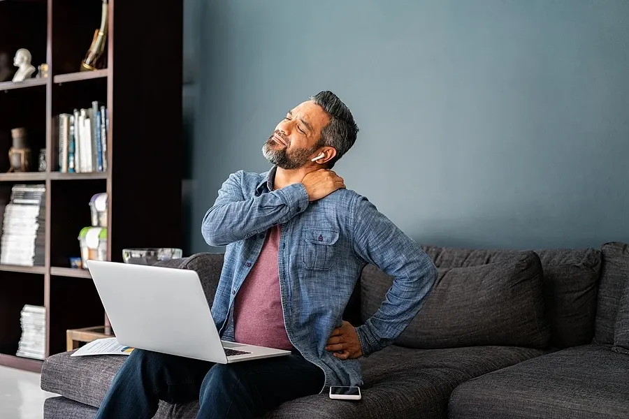 Man sitting at computer holding back of neck in pain