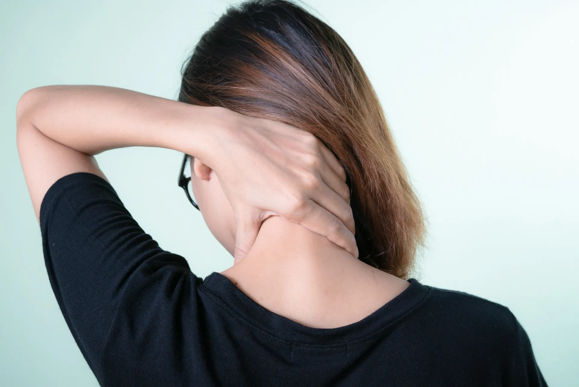 woman holding back of neck in pain